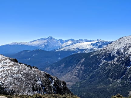 Snow covered mountains with green alpine trees in the valley on a sunny day