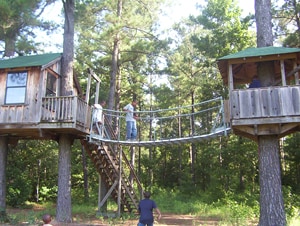 Scouts walking the suspension bridge between two tree houses at Camp TL James.