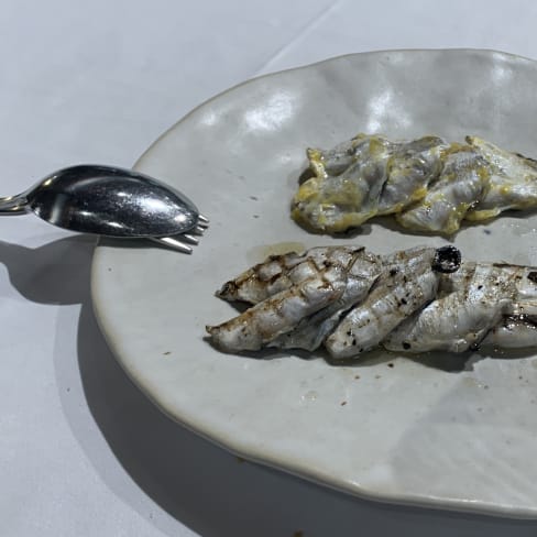 Plato de pescado con filetes a la parrilla y finas láminas de pescado crudo, acompañado de una salsa ligera que resalta la frescura del marisco.
