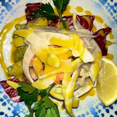 Bunte Salatvariation mit dünn geschnittenem Gemüse wie Radieschen und Gurken, garniert mit einer gelben Zitrus- oder Senfsauce und frischen Kräutern wie Petersilie, serviert mit einem Zitronenschnitz.