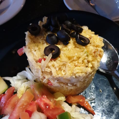 Arroz temperado com azeitonas pretas, acompanhado de uma salada fresca de tomates, pimentos verdes, cebolas e alface, proporcionando um contraste de texturas e sabores.