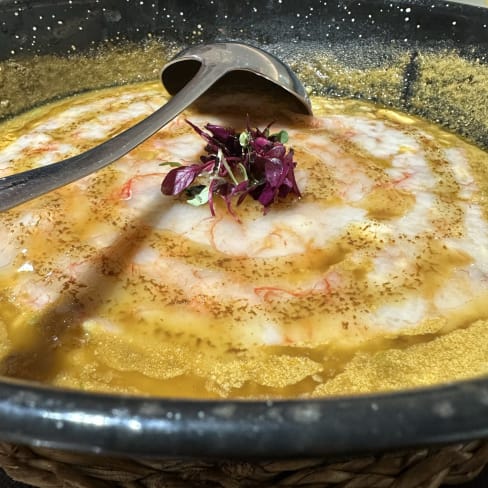 Plato de mariscos con salsa dorada, camarones frescos en espiral y microgreens como guarnición.
