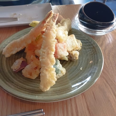 Tempura generosa con camarones crujientes y verduras fritas como calabacín, batata y pimiento, acompañada de salsa de soja.