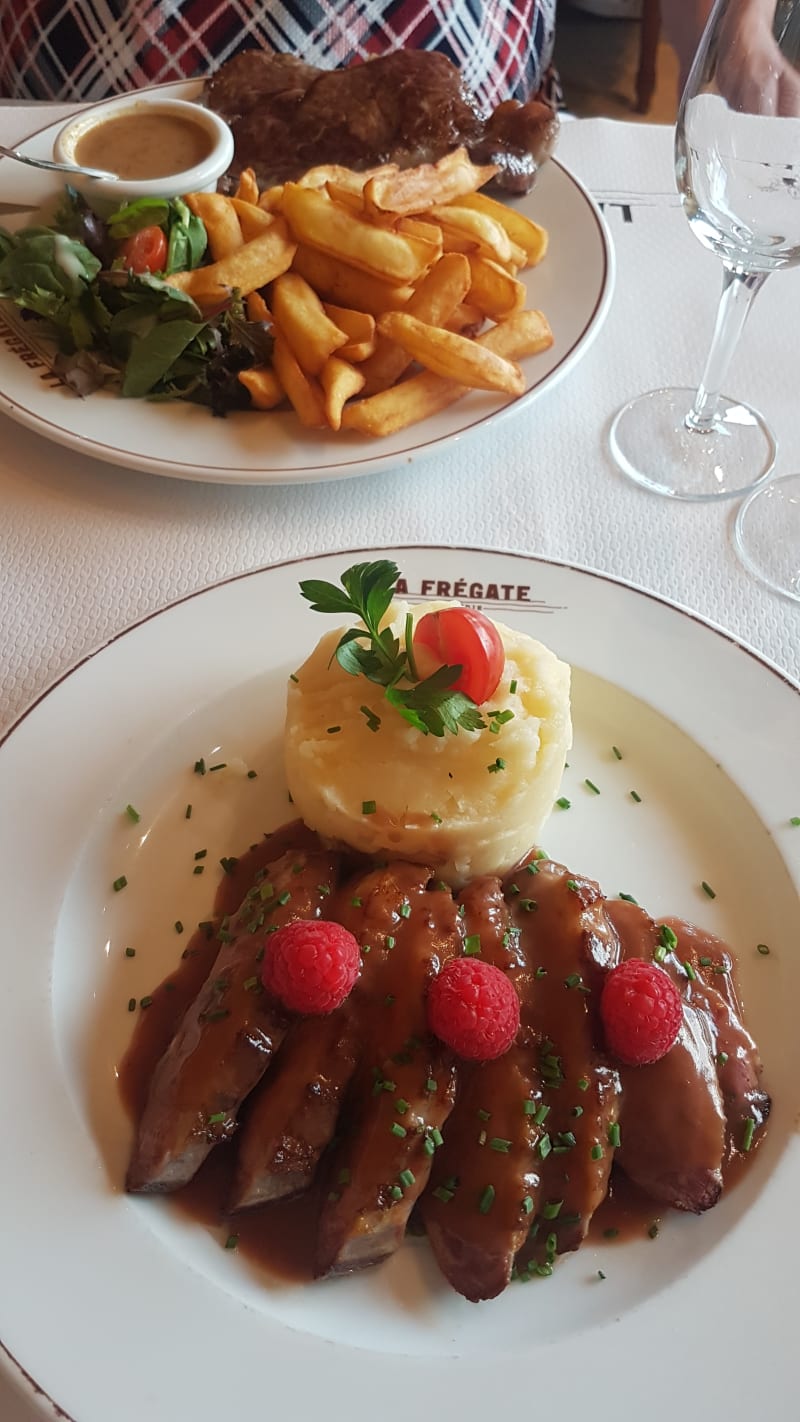 Magret de canard rôti aux framboises, purée maison. En arrière plan: Filet de bœuf, sauce au poivre, frites maison - La Frégate, Paris