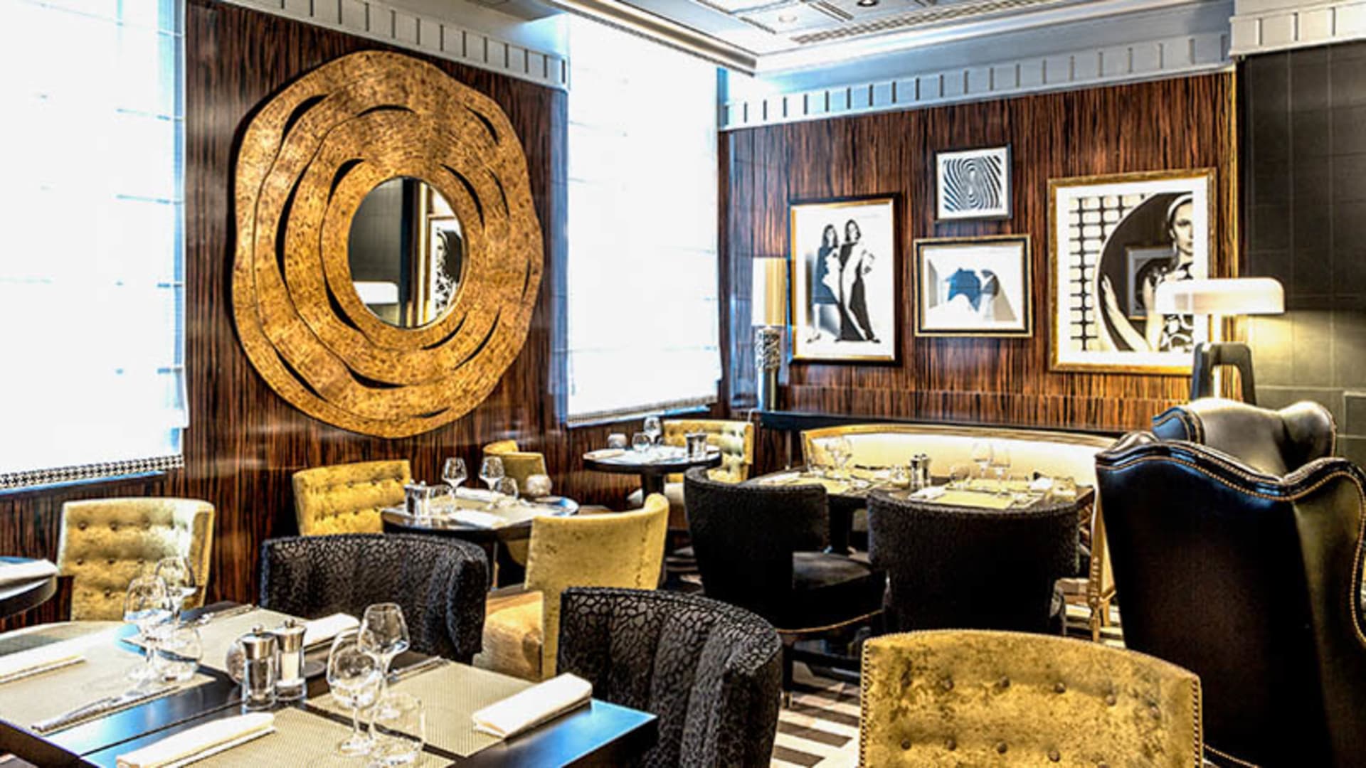 Intérieur du restaurant au design sophistiqué, avec des panneaux en bois foncé, des œuvres encadrées, et un éclairage ambiant, créant une atmosphère élégante et raffinée.