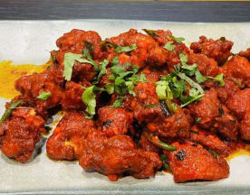 Spicy, tender chicken coated in a rich red sauce, garnished with fresh cilantro and green chili pieces for added heat.