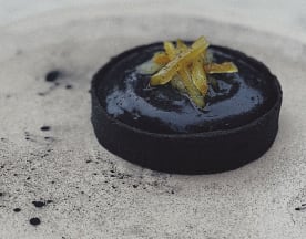 Dessert sophistiqué avec un extérieur noir brillant, garni de fines lanières d'écorce d'agrumes confites, offrant un contraste de couleur et une touche de douceur.
