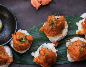 Sushi met kleine rijstballen, belegd met een pittige tonijnmix en gegarneerd met fijngehakte lente-uitjes, geserveerd met wasabi en ingelegde gember.