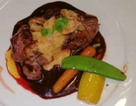 Plat magnifiquement présenté avec un morceau de viande tendre, probablement du bœuf, surmonté d'une épaisse sauce crémeuse. Accompagné de légumes colorés, tels que des carottes orange vif, des poivrons jaunes et des pois mange-tout verts, le tout agrémenté d'herbes fraîches.