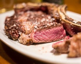 Un jugoso ribeye a la parrilla, con una corteza caramelizada y un centro rosado, sazonado con sal gruesa, ideal para los amantes de la carne.