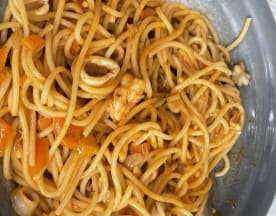 Espaguetis al dente con salsa sabrosa, pollo tierno y pimientos, decorados con hierbas.