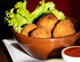 Bol de croquettes dorées et croustillantes, à base de pommes de terre ou de fromage, accompagnées de sauces dip rouge et crémeuse.