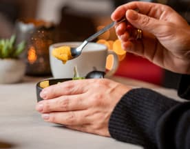 Dessert crémeux, probablement une mousse ou une crème, garni d'une purée de fruits et d'une feuille de menthe, accompagné d'une boisson et d'un verre de vin pétillant.