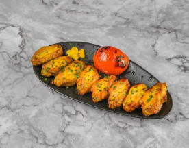 Crispy golden-brown chicken wings seasoned with herbs, accompanied by a roasted tomato for added sweetness and acidity.