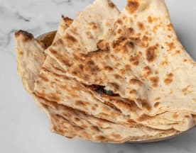 Freshly baked flatbreads with a golden-brown surface and soft texture, featuring a rustic appearance with visible bubbles, ideal for scooping dips or accompanying savory meals.