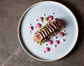 Tonno scottato con crosta di sesamo, servito con salsa rosa e punti bianchi cremosi.