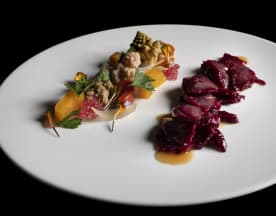 Piatto elegante con frutti di mare teneri e verdure croccanti, accompagnato da carne scura affumicata e una salsa lucida.