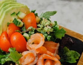 Salada fresca com mistura de folhas verdes, abacate cremoso, tomates-cereja doces e tiras de salmão fumado, guarnecida com flores comestíveis e ervas.