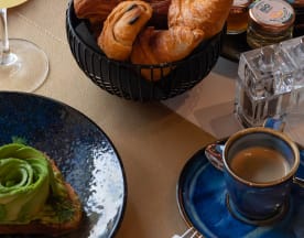 Plat d'avocat sur pain grillé, avec une garniture d'avocat crémeux en forme de rosette, accompagné de croissants dorés et d'un café espresso.