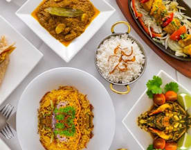 A creamy pasta dish with herbs and melted cheese, surrounded by golden-brown spring rolls, aromatic curry with tender meat, fluffy white rice, and a colorful stir-fried vegetable medley.