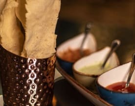 Crackers crujientes, acompañados de tres salsas: una verde suave, una roja dulce o picante, y una mezcla marrón especiada.