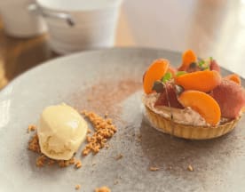 Tarta delicada con relleno cremoso, cubierta de albaricoques frescos y frutas rojas, acompañada de helado cremoso y migas de galleta.