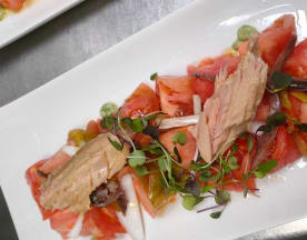 Ensalada fresca de tomates jugosos con atún tierno y microgreens, aderezada sutilmente.