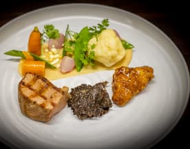 Schweinegericht mit perfekt gebratenem Fleisch, serviert mit einer reichhaltigen dunklen Sauce, bunten Gemüsebeilagen, einer cremigen Blumenkohlpüree und einem süßen oder säuerlichen Glasur.
