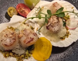 Seared scallops on creamy sauce, garnished with foam, heirloom tomatoes, yellow beet, microgreens, and a wedge of lime.
