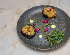 Baked savory grain or legume portions garnished with creamy sauce, microgreens, radish slices, and whole berries.