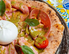 Pizza rustica con burrata, prosciutto, pomodorini, pesto e noci croccanti.