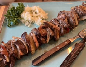Gegrillte Fleischspieße mit zartem Rindfleisch, Zwiebel- und Pilzstücken, serviert mit einem Haufen fein gehobeltem Kohl für einen erfrischenden Kontrast.
