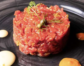 Tartare di manzo finemente tritato, guarnita con erbe fresche, salse cremose e capperi.