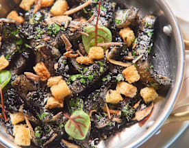 Mistura de legumes salteados, possivelmente com vegetais grelhados, servida com um molho escuro e rico. Os legumes são guarnecidos com pequenos croutons crocantes e ervas frescas, proporcionando um toque de sabor terroso. Uma opção equilibrada e saborosa, ideal para quem procura um prato de vegetais substancial.