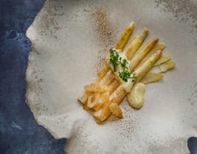 Lightly cooked white asparagus served with a creamy sauce, garnished with fresh herbs and a dusting of seasoning.