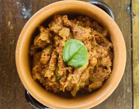 Stufato di fagioli piccante, con una miscela di fagioli in una salsa densa e aromatica, guarnito con una foglia di basilico fresco.