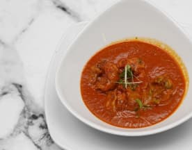 Rich tomato-based curry with tender meatballs, garnished with fresh herbs, offering a hearty and comforting flavor profile.