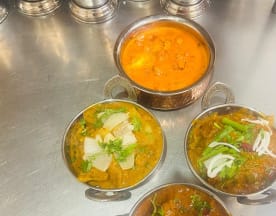 Selección de platos indios que incluye un curry cremoso de tomate y especias, y dos guisos ricos con carne y verduras, uno decorado con cilantro fresco y cebolla, y el otro con pimientos verdes y hierbas.