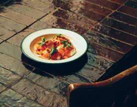 Raviolis généreusement farcis d'une garniture crémeuse, légèrement nappés d'une sauce chaude à base de tomate ou de poivron rôti, garnis d'herbes vertes finement hachées.