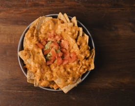 Nachos generosos con salsa de queso cremosa, tomates frescos y guacamole.