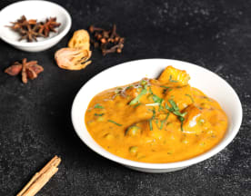 Creamy curry with tender chicken or lamb in a spiced sauce, garnished with fresh cilantro and accompanied by whole spices like star anise and cinnamon.