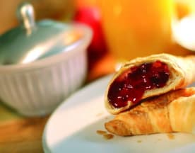Blätterteiggebäck mit einer goldbraunen Kruste und einer reichhaltigen Füllung aus roter Fruchtmarmelade, wahrscheinlich aus Erdbeeren oder Himbeeren, ideal für Frühstück oder Snack.