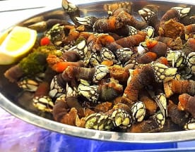 Plato grande con una variedad de mariscos, destacando percebes de colores marrón oscuro a verdosos, acompañados de rodajas de limón.