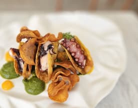 Tacos crujientes rellenos de pulpo a la parrilla, acompañados de salsas verde y amarilla, y decorados con chips de papa.