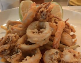 Calamares fritos crujientes y camarones, acompañados de rodajas de lima frescas, ideales como aperitivo para compartir.