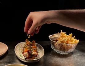 Selectie van zeevruchten met gegrilde garnalenspiesjes, gegarneerd met verse kruiden en saus, en een bijgerecht van krokante frietjes met een romige dipsaus.