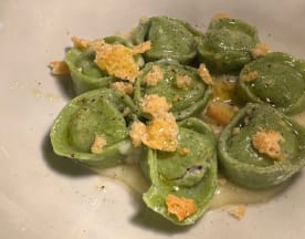 Pasta verde rellena con una mezcla rica, cubierta con una salsa cremosa y crujientes dorados, decorada con pimienta negra.