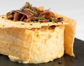 Plato cremoso de queso o natillas, con carne de pato cocida lentamente y decorado con cebollino picado y una oblea crujiente.