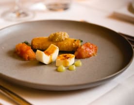 Gerolltes Gericht mit einer goldbraunen, knusprigen Hülle, gefüllt mit einer herzhaften Füllung, serviert mit einer reichhaltigen Tomatensauce und kleinen, cremigen Kugeln, möglicherweise Käse oder Püree, sowie einem Hauch von Senf.