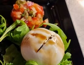 Gerecht met romige burrata kaas, gegarneerd met een scheutje balsamico-reductie, omringd door frisse groenten en een salade van blokjes tomaat, kappertjes en rode ui.